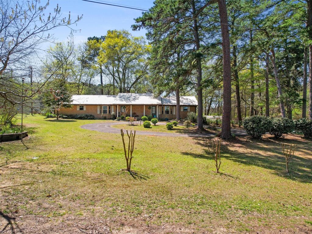 View of front facade featuring asphalt driveway, a front lawn, and metal roof
