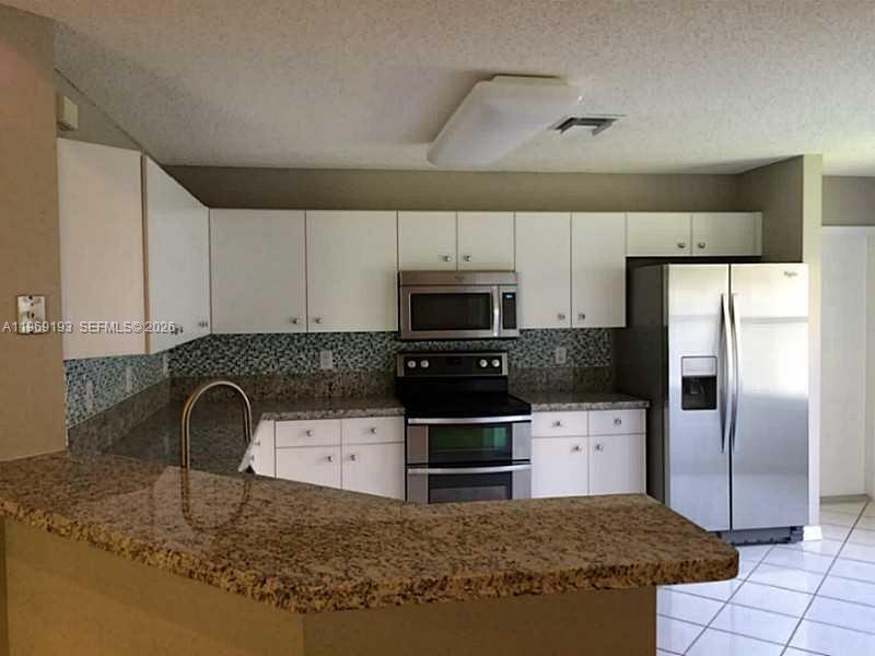 1653 Zenith Way Weston, FL 33327 - Photo 6 of 22 a kitchen with stainless steel appliances granite countertop a sink a stove and a refrigerator