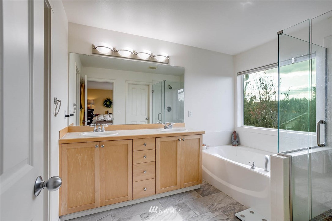 27555 Maple Ridge Way Southeast Maple Valley, WA 98038 - Photo 14 of 25 a bathroom with a tub a double vanity sink a toilet a mirror and vanity