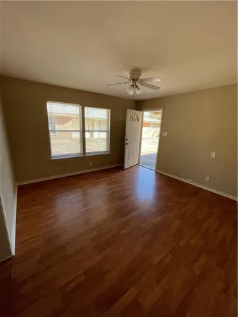 an empty room with wooden floor and windows