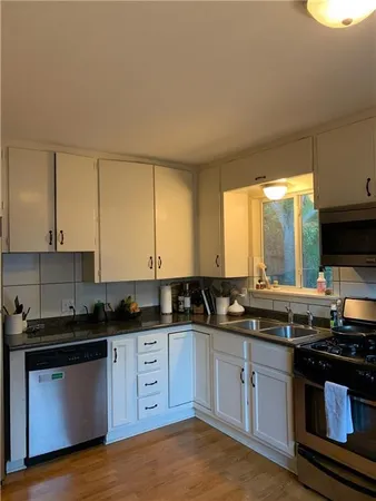 a kitchen with stainless steel appliances granite countertop a sink a stove a counter space and cabinets