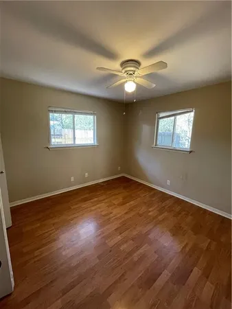 a view of empty room with wooden floor and fan