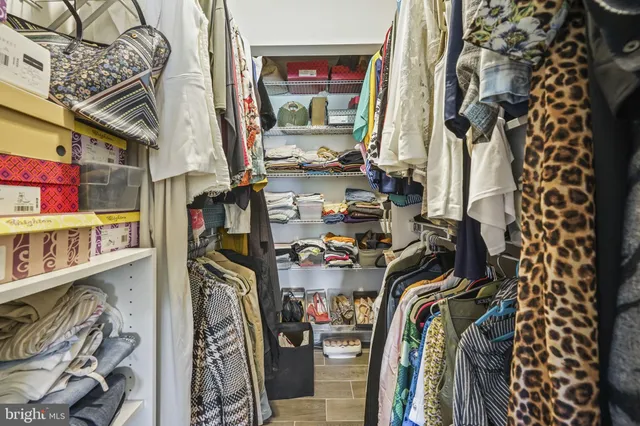 a view of walk in closet with clothes and shoes