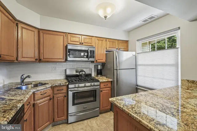 a kitchen with granite countertop a refrigerator stove and microwave