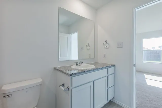 a bathroom with a granite countertop sink a toilet and a mirror