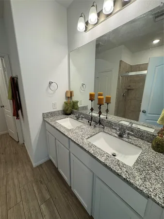 a bathroom with a granite countertop double vanity sink and mirror