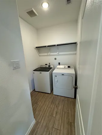 a utility room with wooden floor washer and dryer