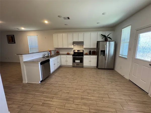 a kitchen with stainless steel appliances granite countertop a stove top oven a refrigerator a sink and dishwasher