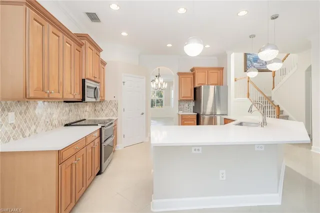 a large kitchen with stainless steel appliances a large counter top a stove and a sink
