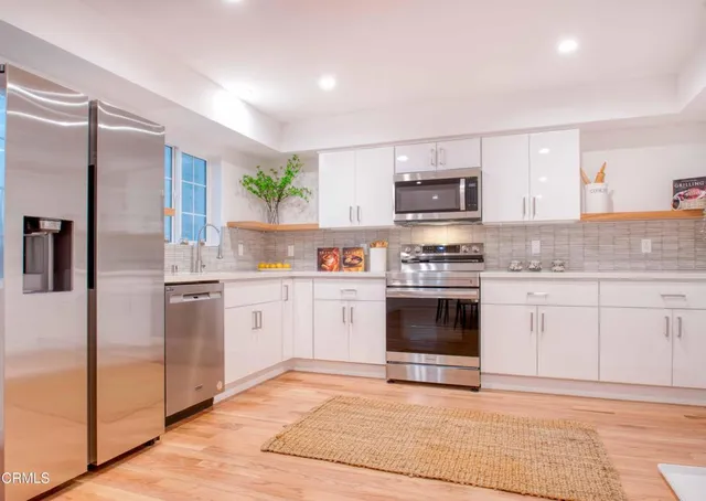 a kitchen with granite countertop a refrigerator and a stove top oven