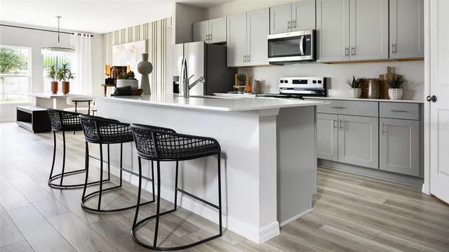 a kitchen with stainless steel appliances kitchen island granite countertop a stove a sink and a refrigerator with wooden floor