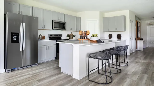 a kitchen with stainless steel appliances a stove a sink refrigerator and a microwave with wooden floor