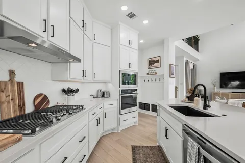 a kitchen with stainless steel appliances a sink stove and white cabinets