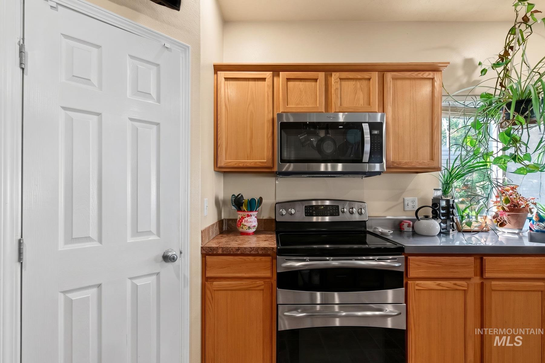 5020 Northrup Way Caldwell, ID 83607 - Photo 16 of 36 Kitchen featuring a stainless steel range, coordinating stainless steel microwave, light wood-finish cabinetry, and a window with natural light