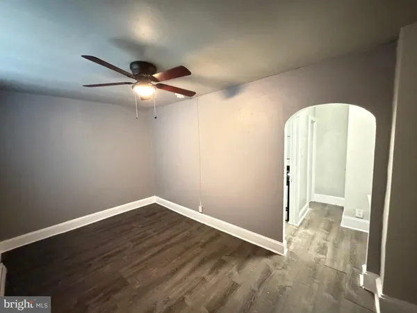 an empty room with wooden floor and fan