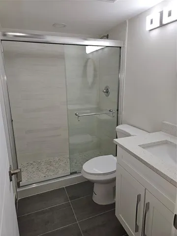a bathroom with a granite countertop toilet a sink and a shower