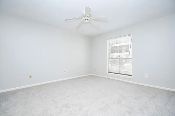 an empty room with a window and a fan