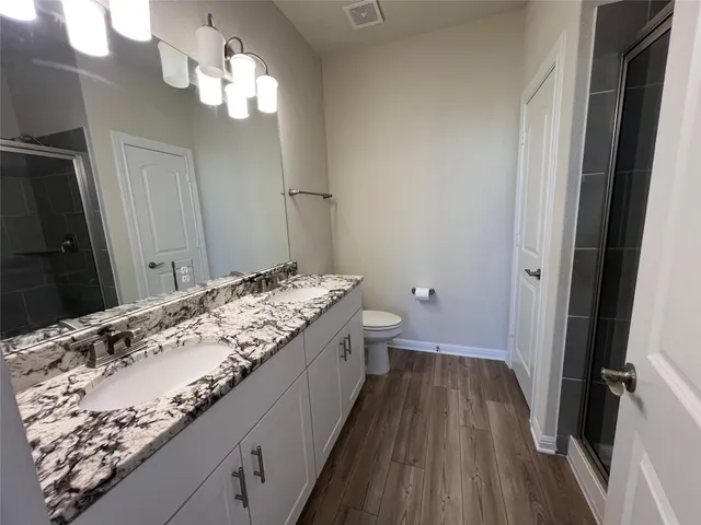 a bathroom with a granite countertop sink a mirror and shower