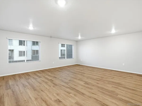 a view of an empty room with wooden floor and windows