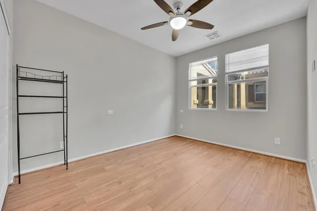 an empty room with wooden floor closet and windows