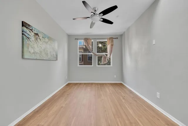 a view of an empty room with a window and wooden floor