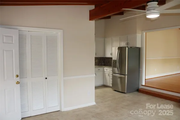 a view of a refrigerator in kitchen and an empty room