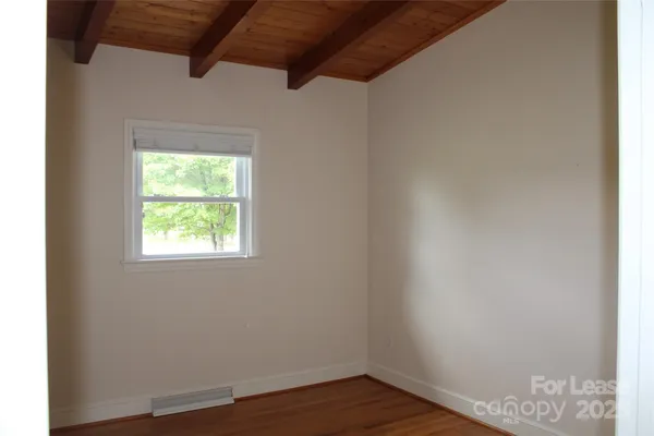 an empty room with wooden floor and a window