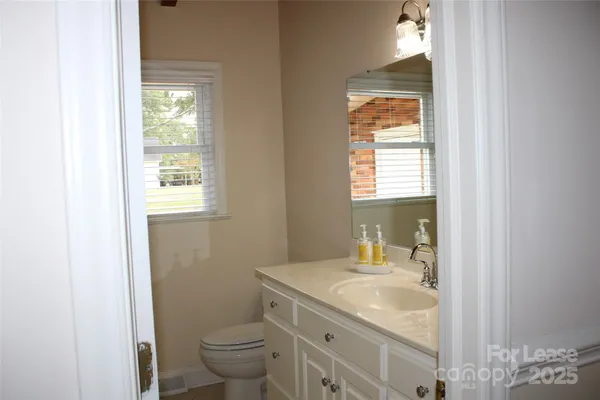 a bathroom with a granite countertop sink toilet and a mirror