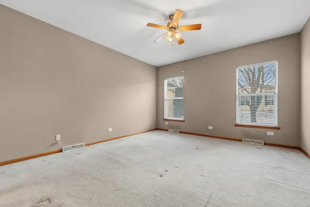 an empty room with windows and fan