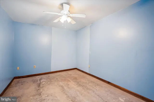 an empty room with a chandelier fan and a window