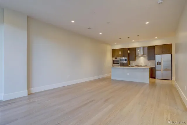 a view of kitchen with kitchen island granite countertop stainless steel appliances refrigerator and microwave