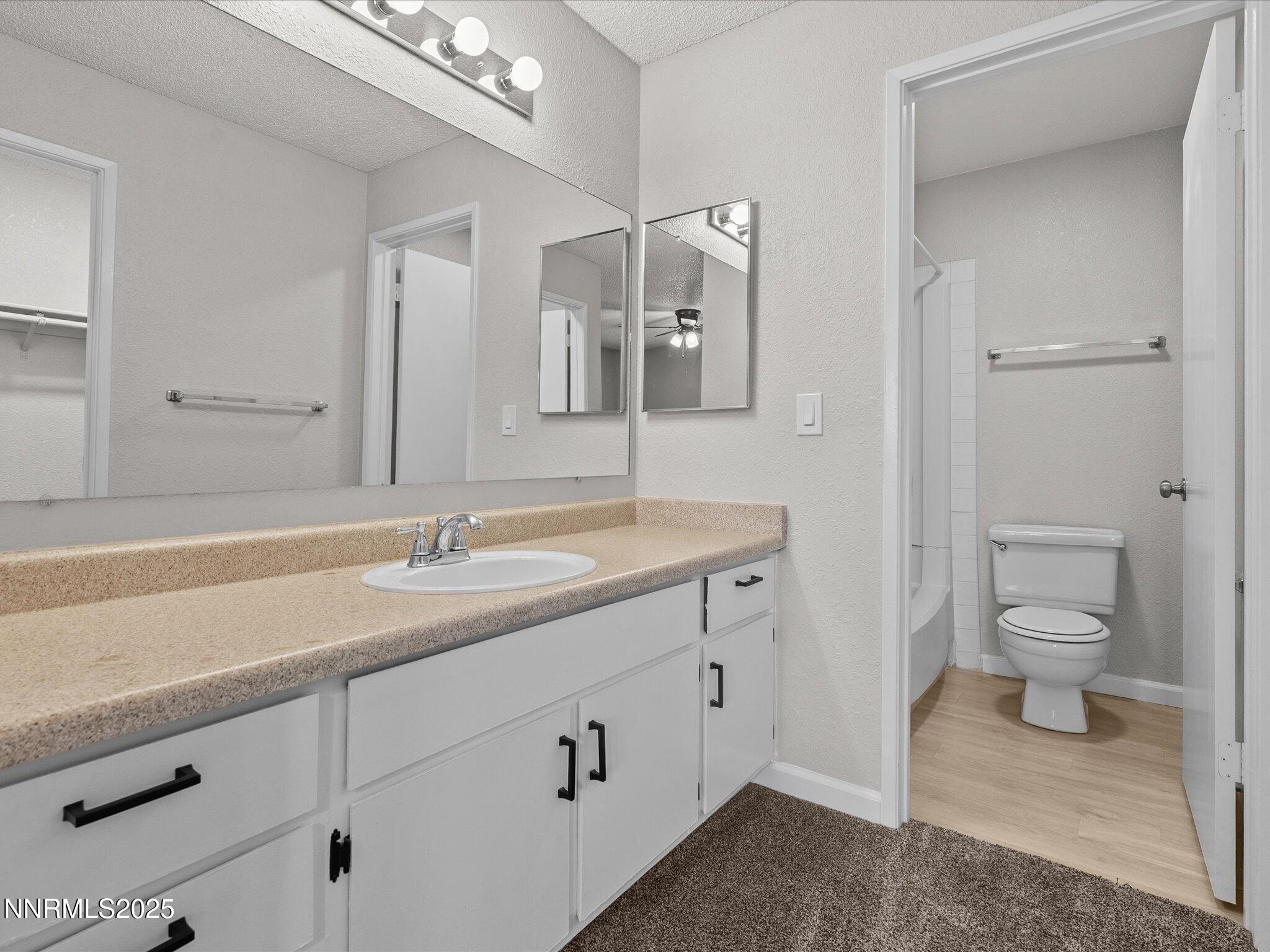 7680 Bluestone Drive, Unit 356 Reno, NV 89511 - Photo 15 of 23 a spacious bathroom with a granite countertop sink a toilet and a mirror