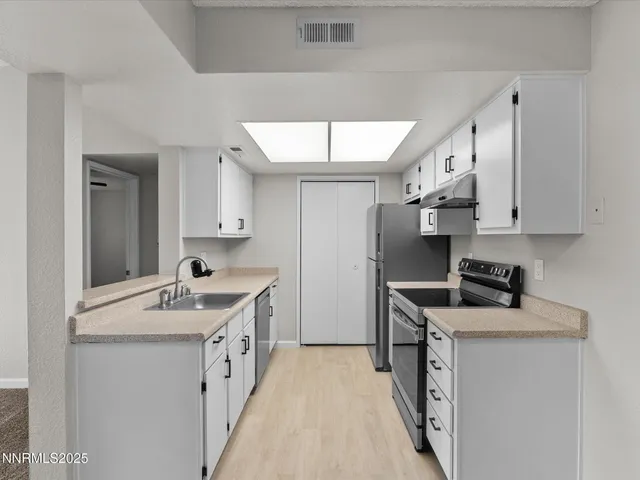 a kitchen with granite countertop a sink stove and refrigerator
