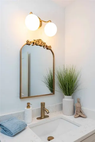 a bathroom with a sink a mirror and a potted plant