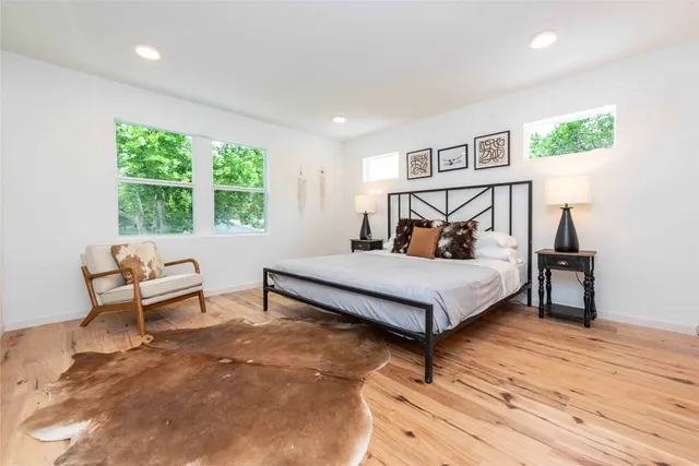 a bedroom with a bed lamp and a large window with wooden floor