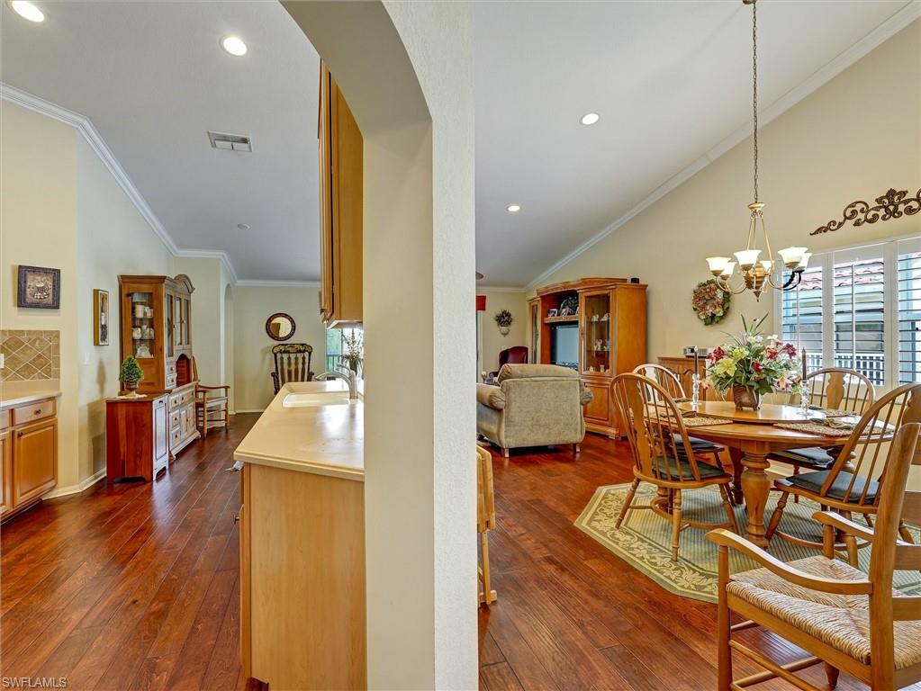 895 Eastham Way, Unit M202 Naples, FL 34104 - Photo 13 of 37 a view of a dining room and livingroom with furniture wooden floor a chandelier