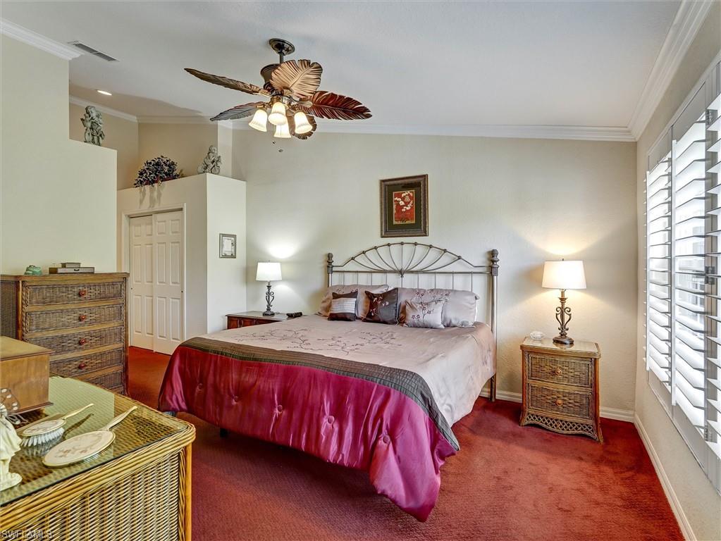 895 Eastham Way, Unit M202 Naples, FL 34104 - Photo 19 of 37 a bedroom with a bed and a chandelier