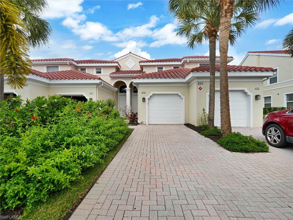 895 Eastham Way, Unit M202 Naples, FL 34104 - Photo 2 of 37 a view of a white house with a yard and potted plants
