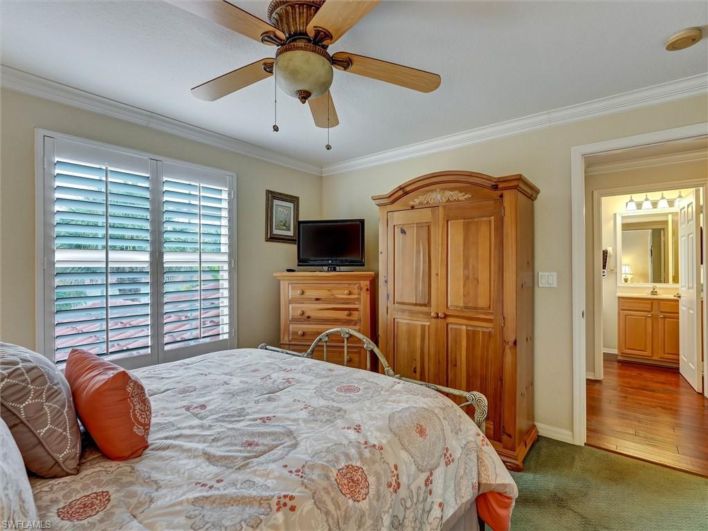 895 Eastham Way, Unit M202 Naples, FL 34104 - Photo 27 of 37 a bedroom with a bed and a chandelier