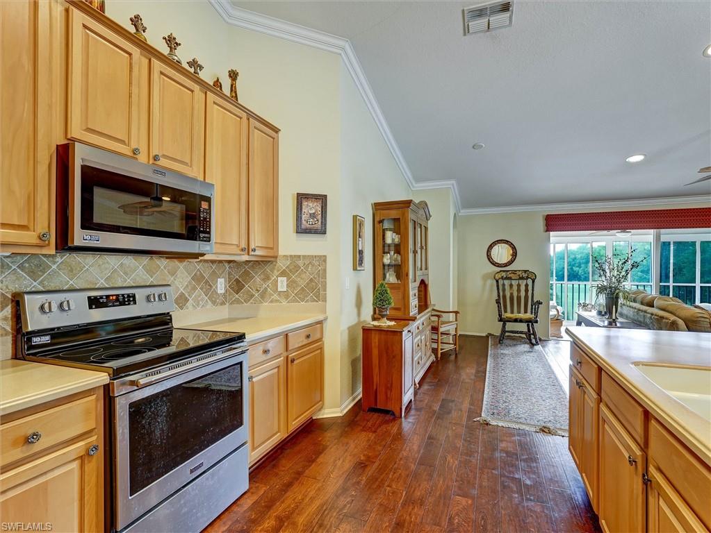 895 Eastham Way, Unit M202 Naples, FL 34104 - Photo 8 of 37 a kitchen with stainless steel appliances a stove sink microwave and cabinets