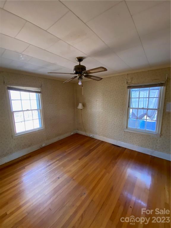 430 Russell Road Polkton, NC 28135 - Photo 14 of 18 an empty room with wooden floor chandelier fan and windows