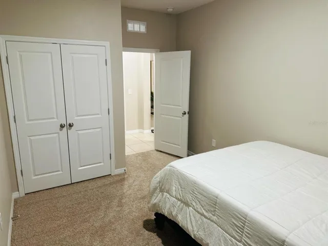 a spacious bedroom with a bed and a cabinet