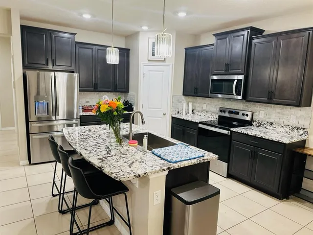 a kitchen with stainless steel appliances kitchen island granite countertop a kitchen island a stove a sink a microwave and a refrigerator