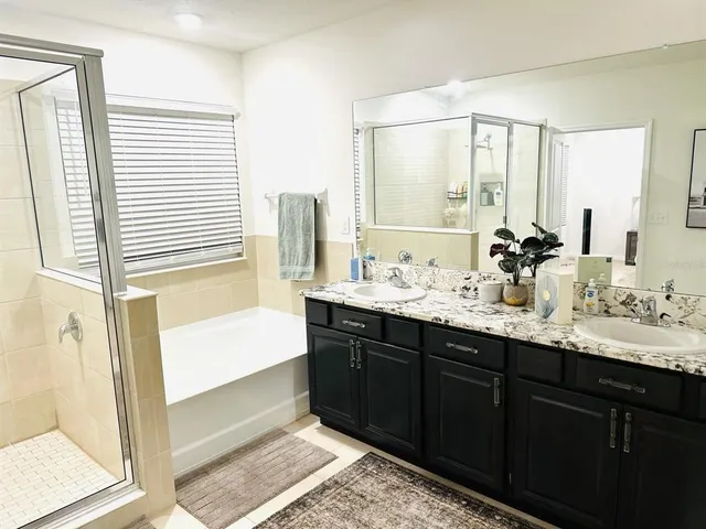 a bathroom with double vanity sinks a mirror and a bathtub