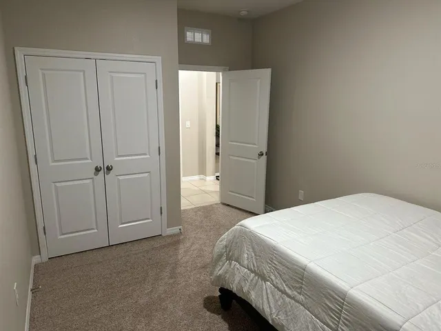 a spacious bedroom with a bed and cabinet