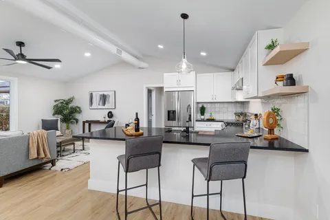 a living room with stainless steel appliances kitchen island granite countertop furniture and a view of kitchen