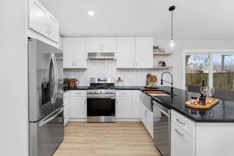 a kitchen with stainless steel appliances granite countertop a sink stove and refrigerator