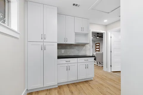 a kitchen with granite countertop white cabinets and stainless steel appliances