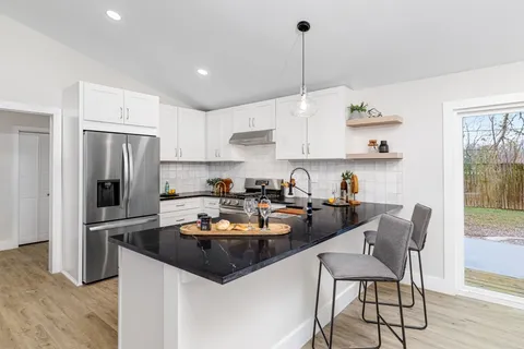 a kitchen with a refrigerator a stove a sink and chairs