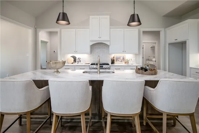 a kitchen with kitchen island granite countertop a dining table chairs and white cabinets